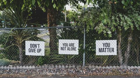Signs on fence that read "Don't Give Up"
